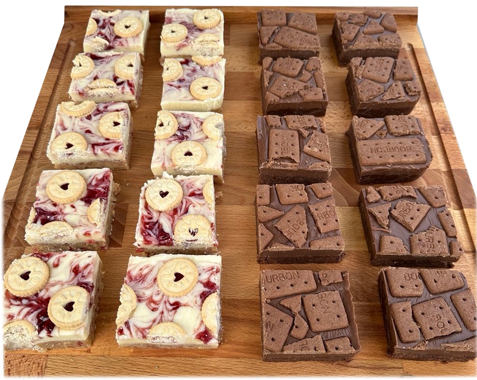 A wooden board of square bakes: white chocolate with a red jam swirl and heart biscuits on one half, chocolate fudge topped with bourbon biscuits on the other.